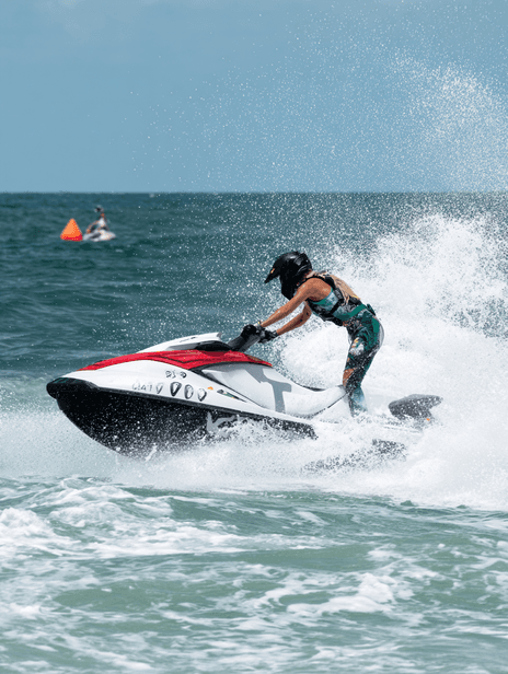 Jet ski riding across crystal-clear Caribbean water under sunny skies.
