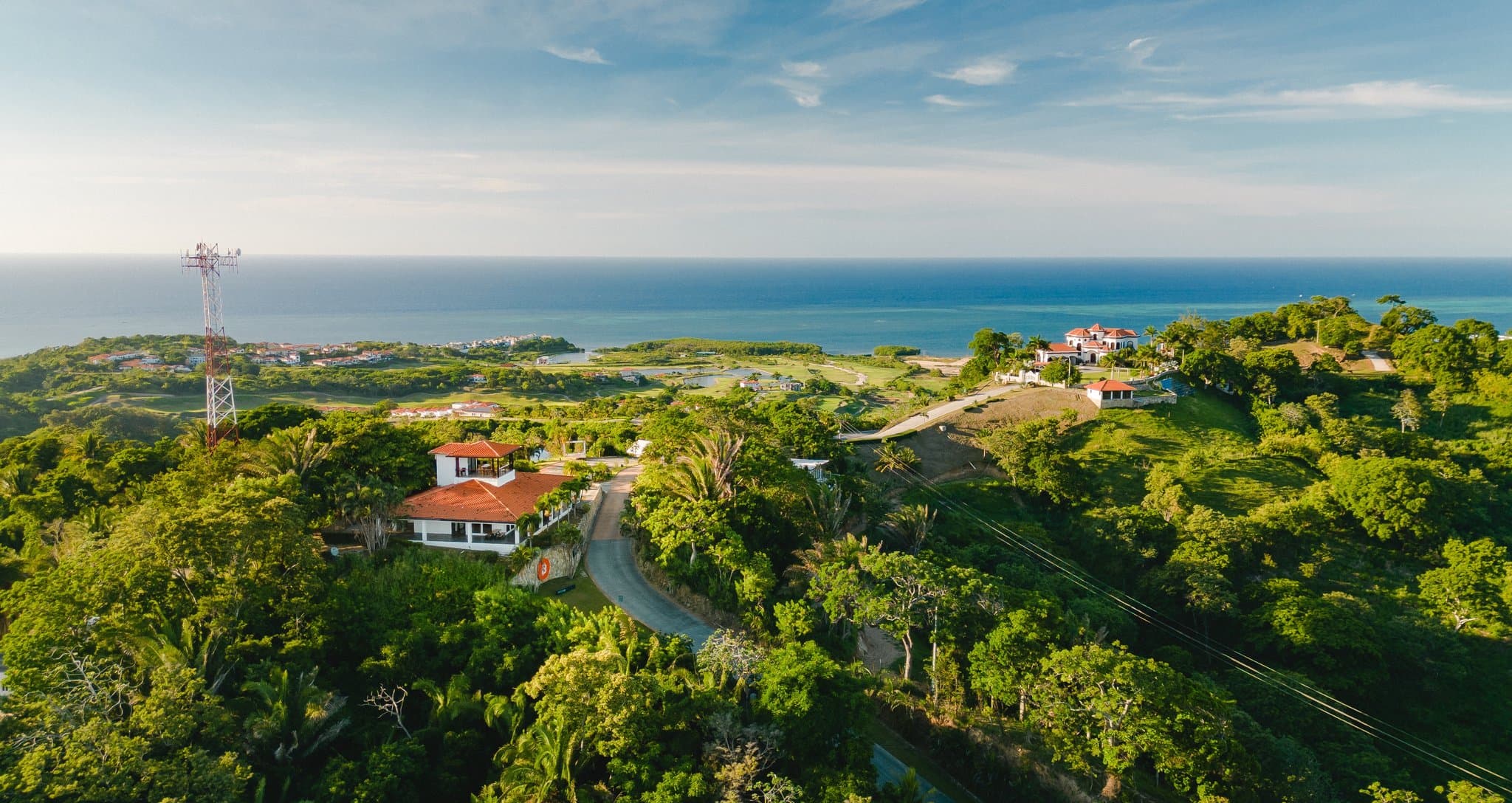 Lujoso dormitorio moderno con vistas panorámicas a la naturaleza, con una gran cama blanca, llamativo arte de pared en blanco y negro, y un innovador diseño de techo de madera. Incluye un acogedor rincón de lectura, mobiliario elegante y una exhibición de bicicletas, perfecto para eco-resorts de lujo o casas vacacionales de alta gama que enfatizan el diseño contemporáneo y la conexión con la naturaleza.
